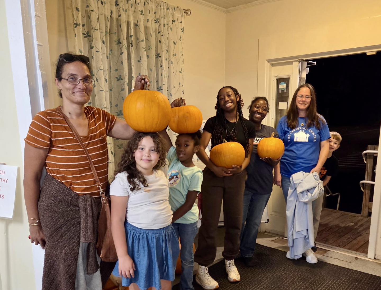 Smiling group holding pumpkins indoors
